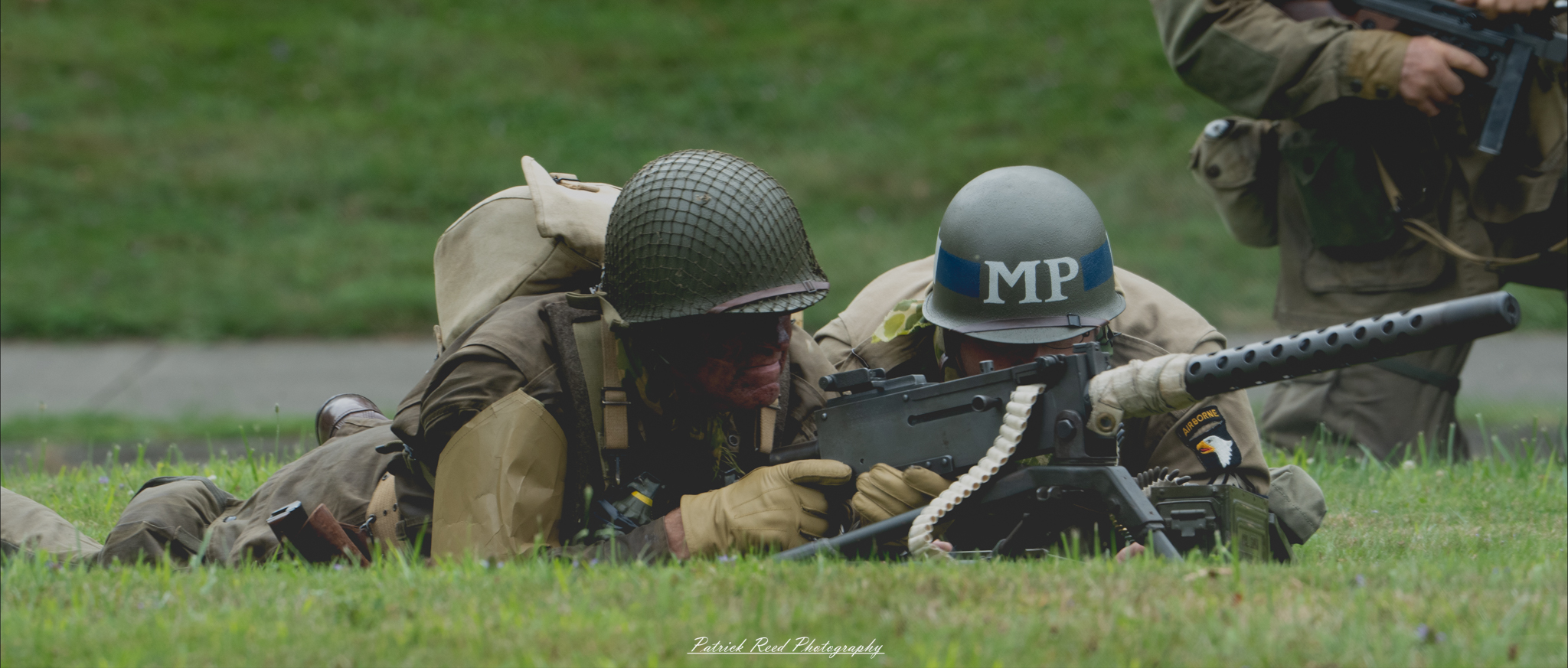 "An intense scene of two soldiers lying prone in a field, firing a .50 caliber machine gun. The image captures the teamwork and concentration required as they operate the powerful weapon amidst the tension of battle."